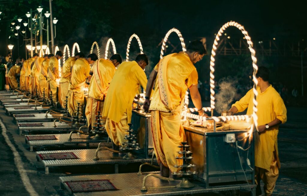 Group of men performing a traditional Hindu ritual ceremony outdoors at night.